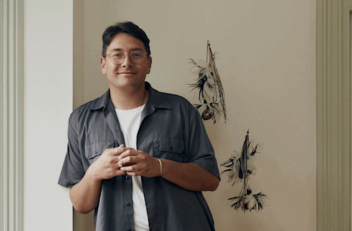 Hāmiora Bailey leans against a wall with a content expression. 