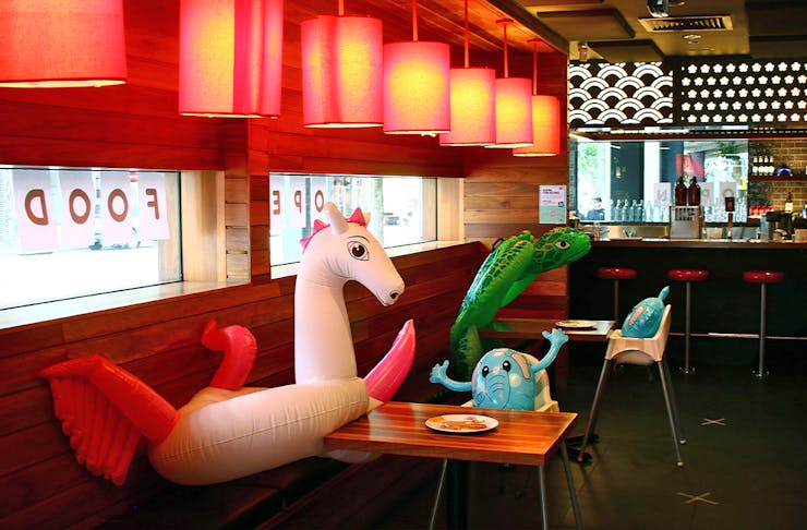 A restaurant with people at some tables, and inflatable animals at other