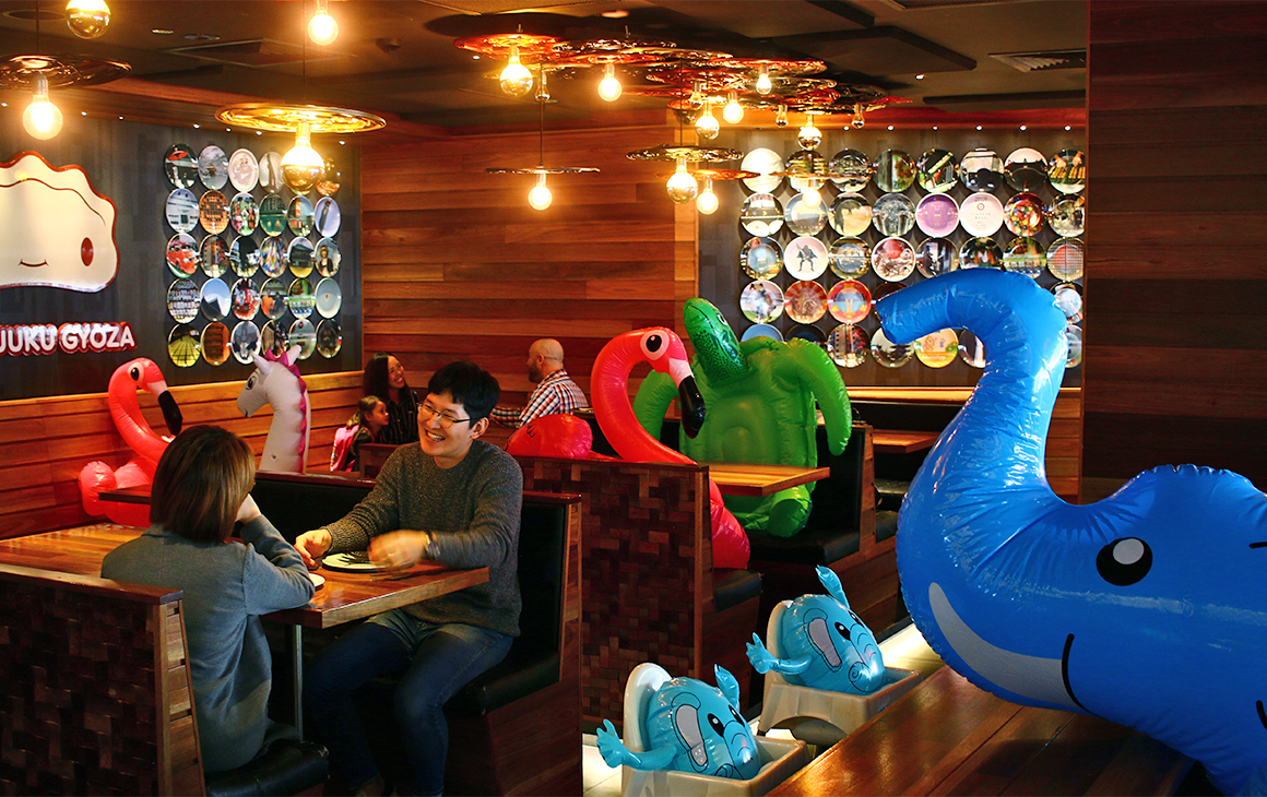 A restaurant with people at some tables, and inflatable animals at other