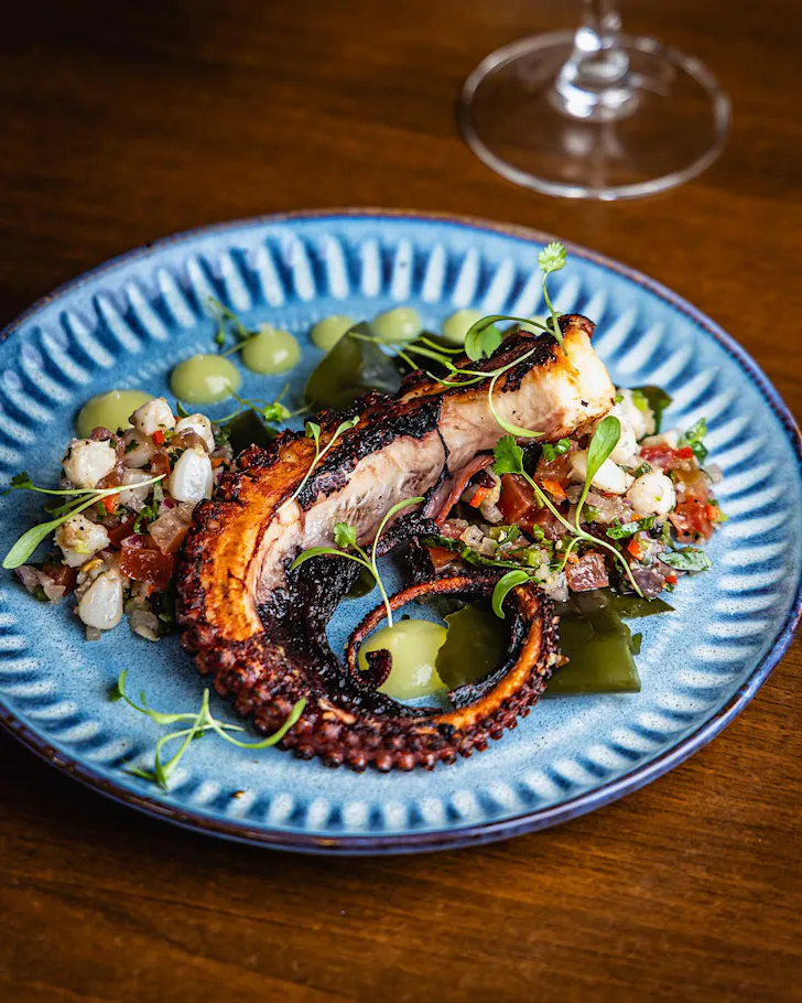 A plate of Fremantle octopus iwth hominy and tomato salsa, jalapneo and mezcal gel, finished with seaweed and coriander.
