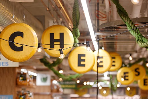 sign hanging from a ceiling saying 'cheese'
