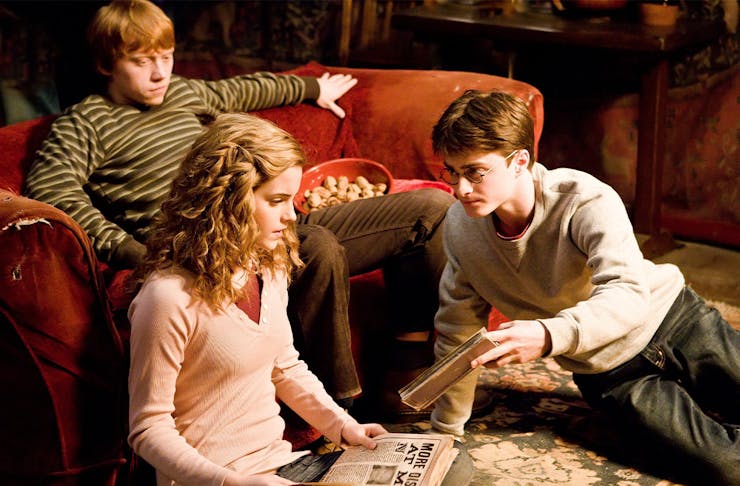 A scene from harry potter, with ron, hermione and harry sitting on a couch