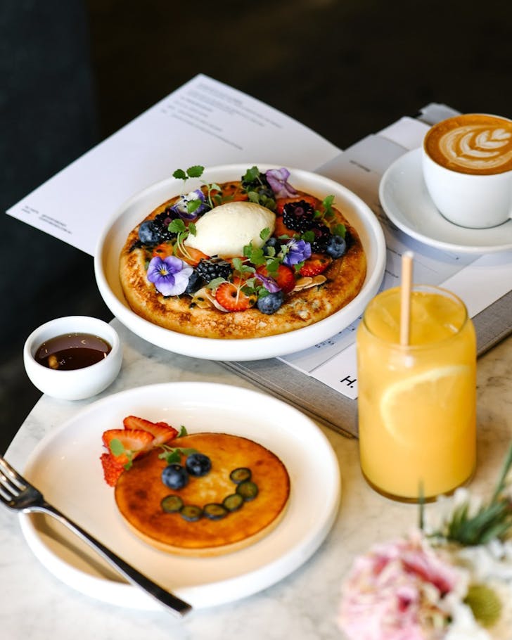 a hotcake dish with berries and flowers, and a flat white at harry's in bondi