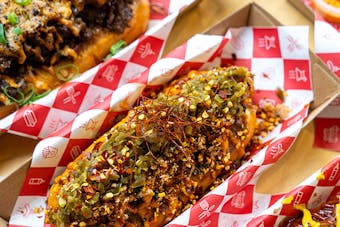 Two hotdogs stacked with toppings.