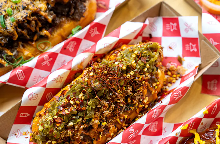 Two hotdogs stacked with toppings.
