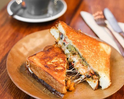 A toasted sandwich oozing with cheese and trimmings.