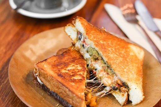A toasted sandwich oozing with cheese and trimmings.