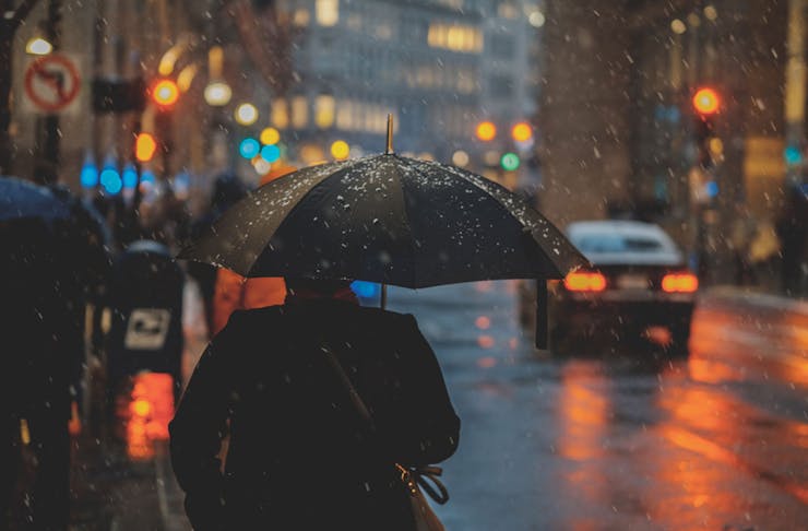 A man holding an umbrella on a dark, rainy day.