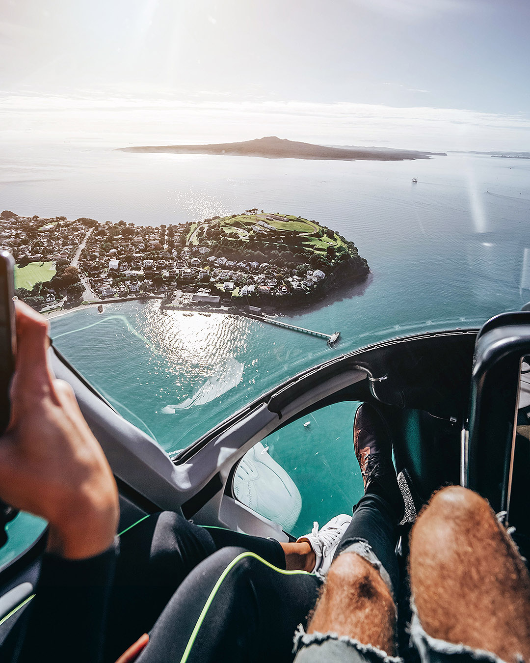 Two people relax as they view Auckland from above in their helicopter.