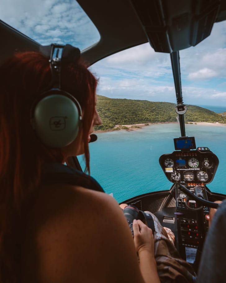 A woman in a helicopter looks out at the view of the sparkling Great Barrier Reef below. 