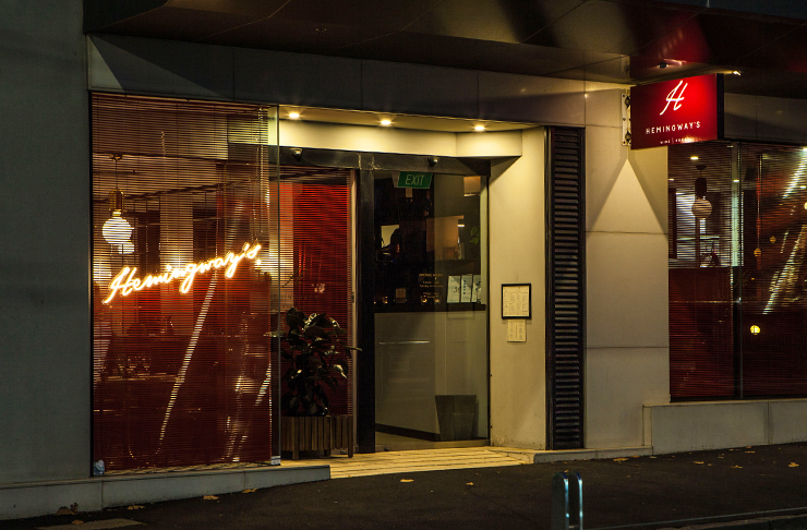 A moody restaurant at night with a red neon sign that reads 