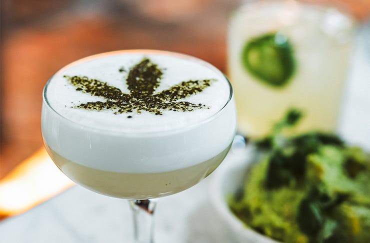 a cocktail with a cannabis leaf design sprinkled on top