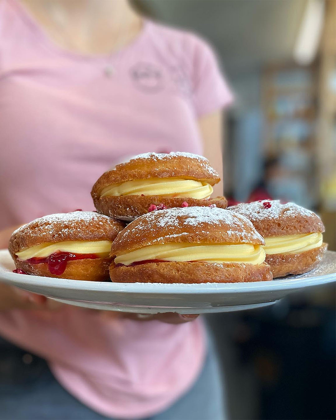 Someone holds Jam and custard donuts at Henry and Ted, one of the best cafes in Tauranga.