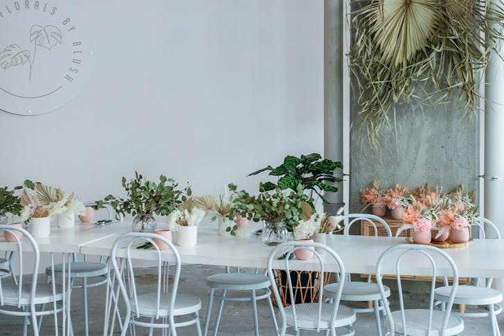 Long White table decorated with pink and white pot plants at Florals By Blush
