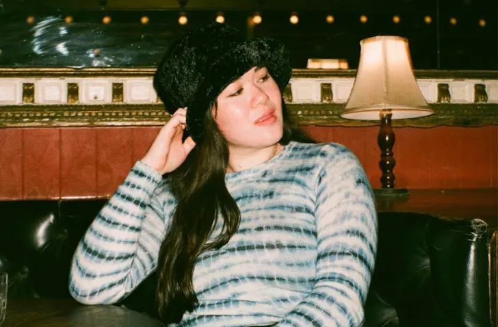Woman sitting at a bar with a black fluffy hat on