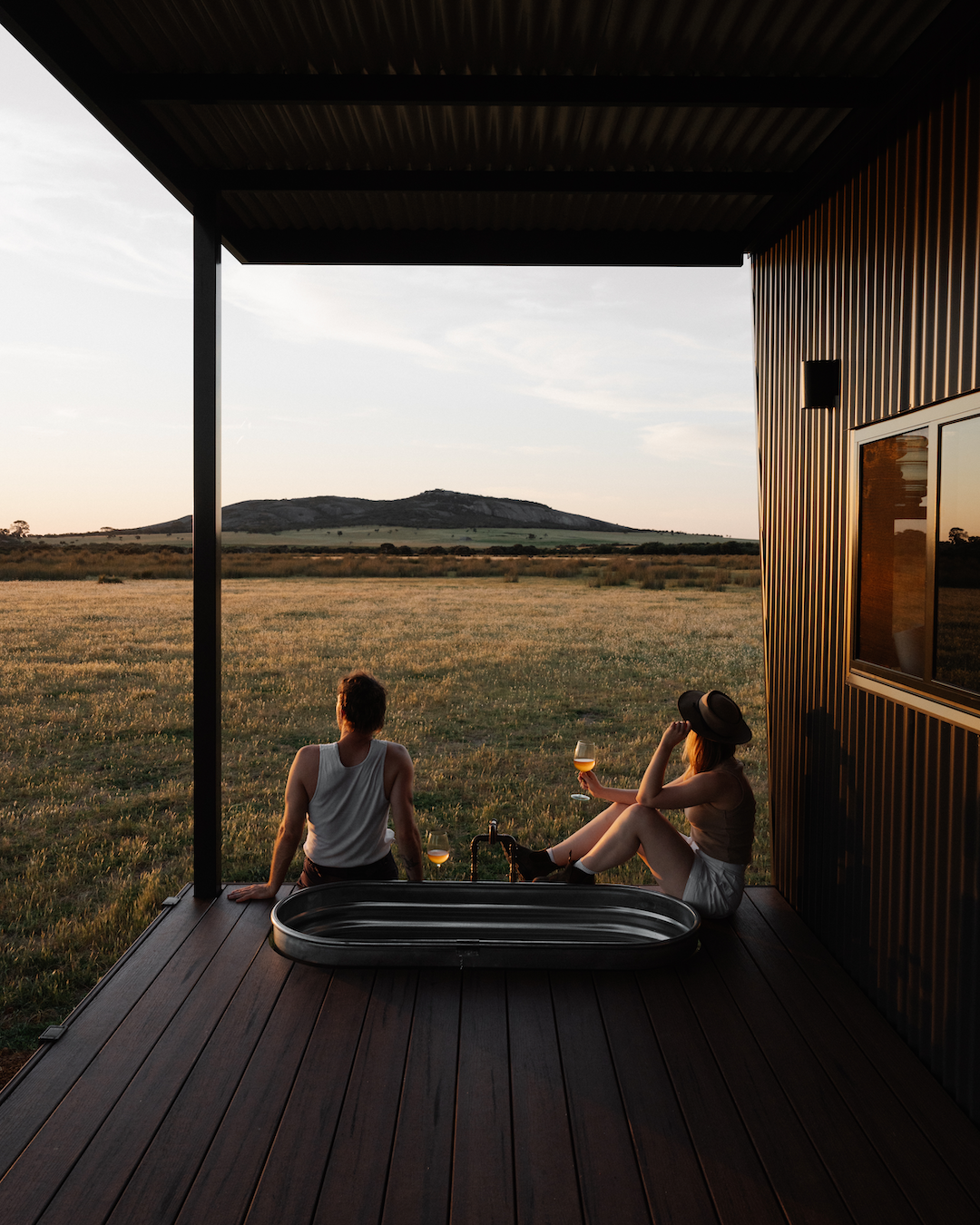 A couple enjoying a wine on the deck of a tiny cabin in Esperance