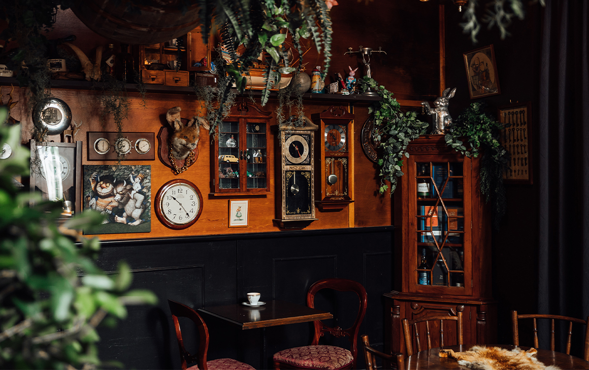 interior of a bar with clocks on the walls and vines hanging from the ceiling