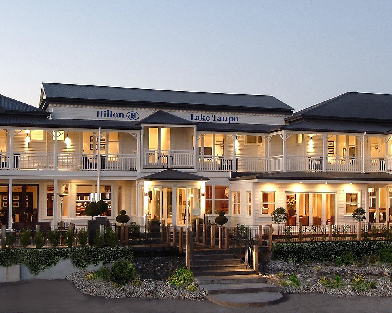 The exterior of Hilton Lake Taupo lit up by lights at dusk.