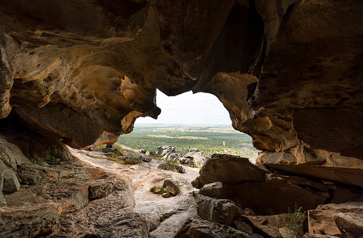 A hollow cave overlooking grass plains.