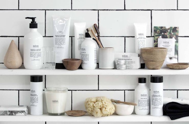 Shelves set upon white subway tiles filled with Salus skin and beauty products.