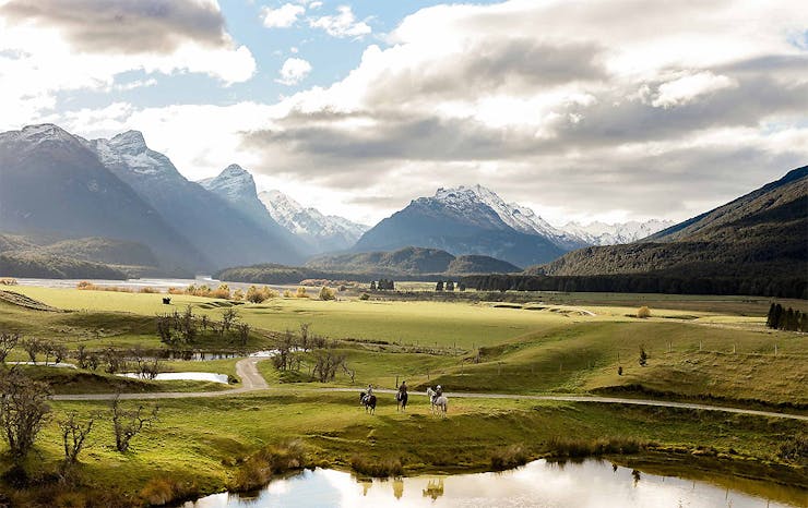 Three people sit on horseback in  stunning Glenorchy