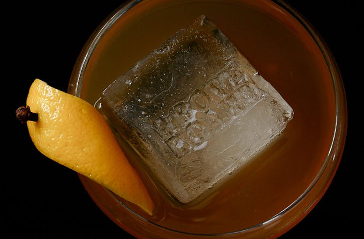 An Amaro Hot Toddy from above, a large ice cube and lemon garnish can be seen.