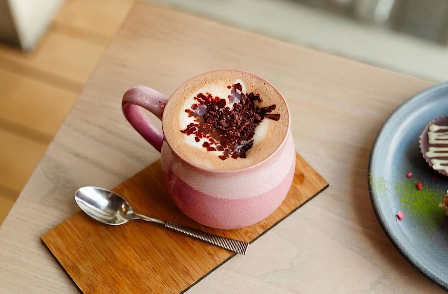 A cute pink mug of hot cacao decorated with chocolate sprinkles in the shape of a heart. 