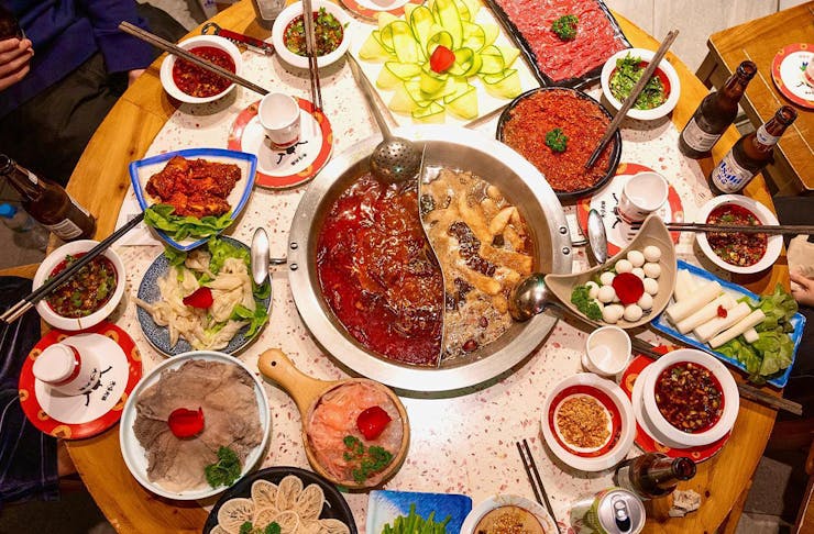 a table with a double pot in the centre surrounded by plates of food