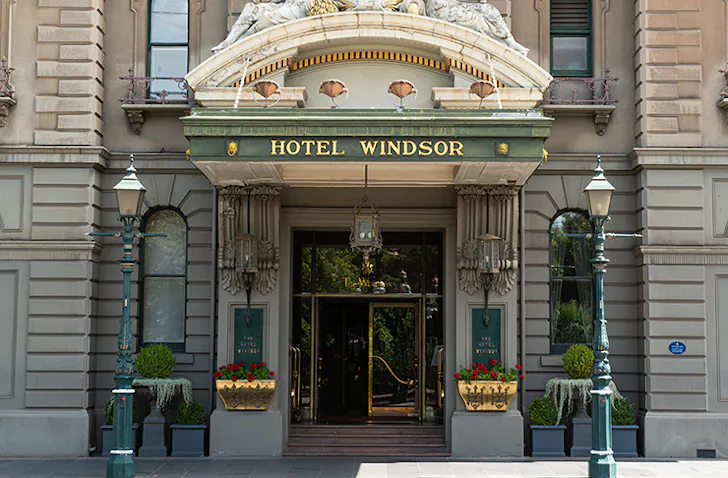 Concrete pillar entry of Hotel Windsor with light beaming across the facade 