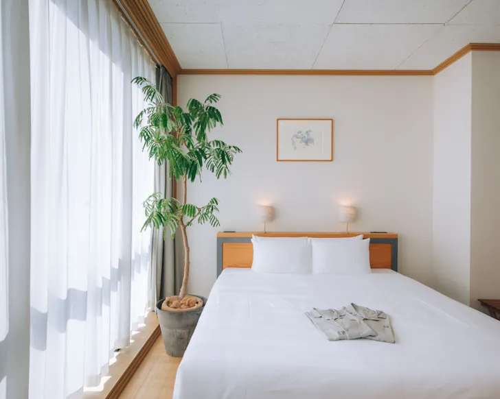 A minimalistic, light-filled room at budget-friendly stay Hotel Noum in Osaka.