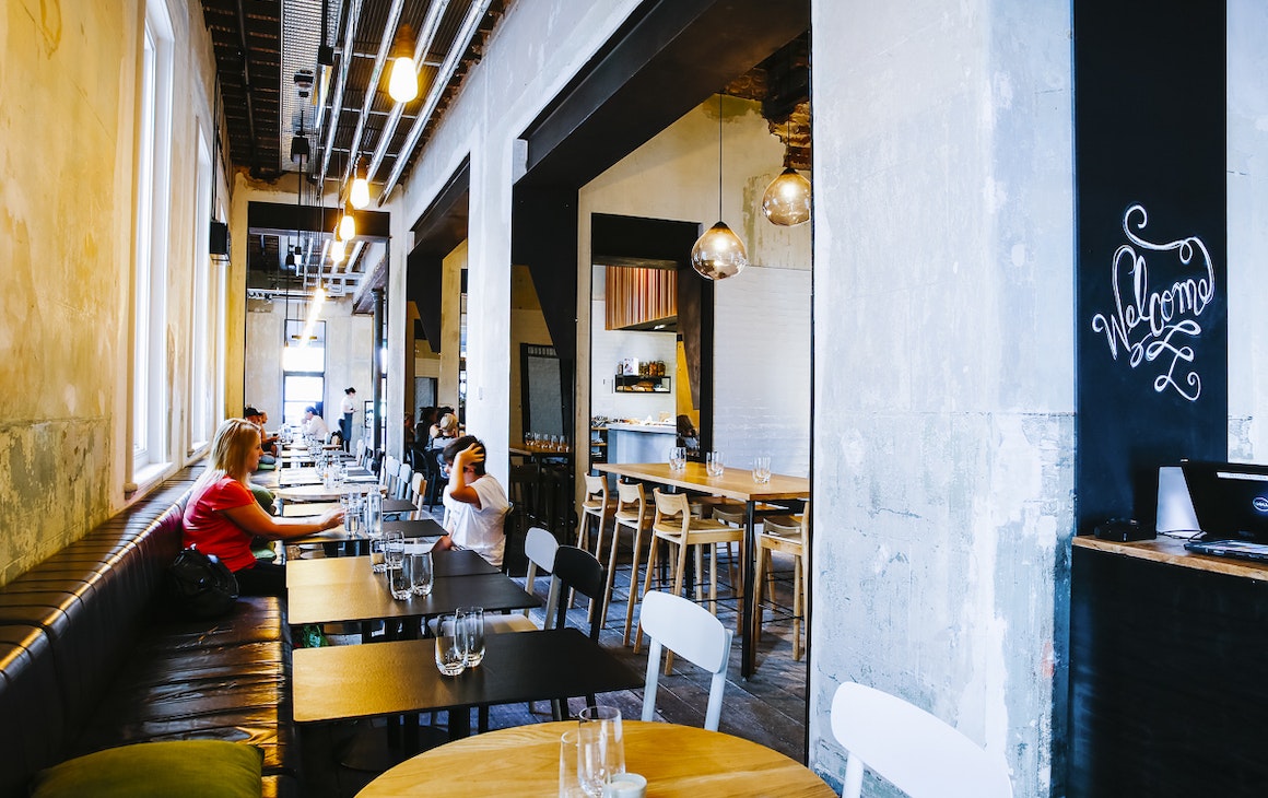 a long booth seat stretching down one side of a restaurant with tables and chairs