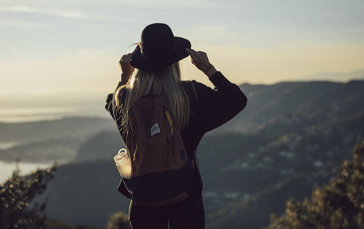 a woman on a mountain top with a backpack and a waterbottle
