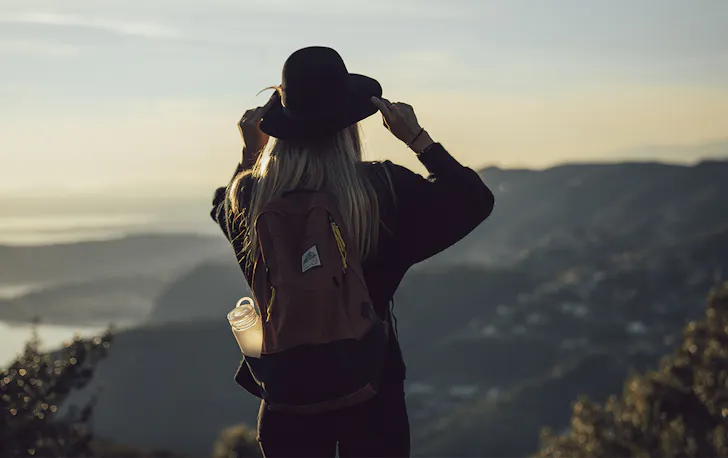 a woman on a mountain top with a backpack and a waterbottle