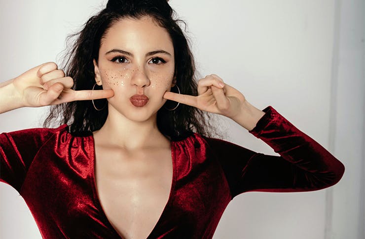 a woman in a red dress pointing at her cheeks