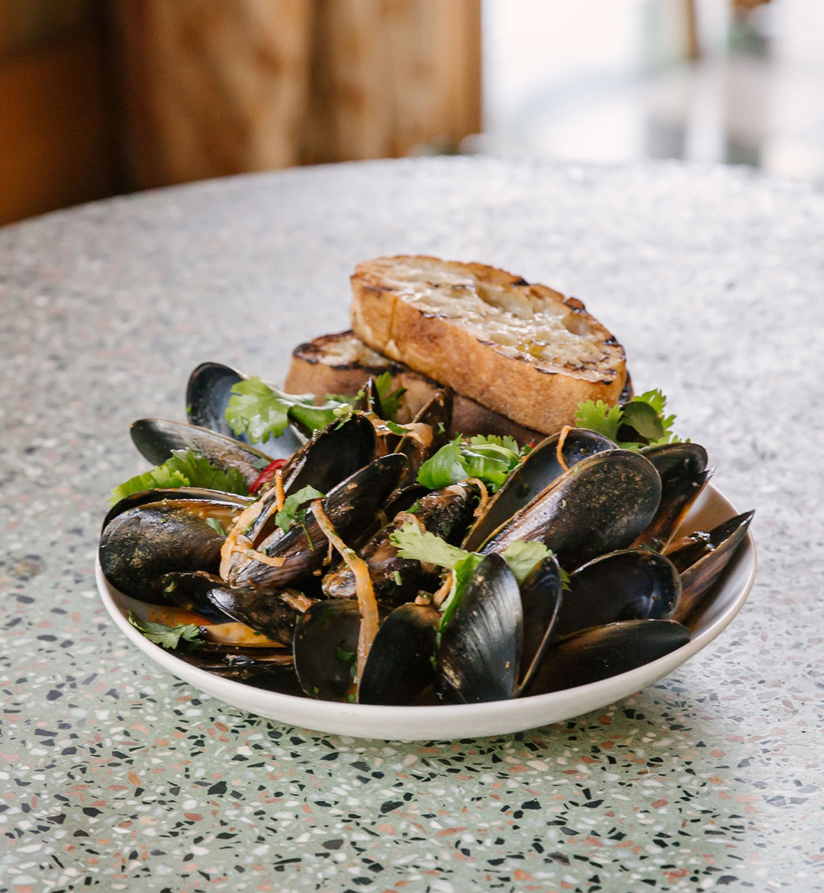 a bowl of mussels topped with crusty bread