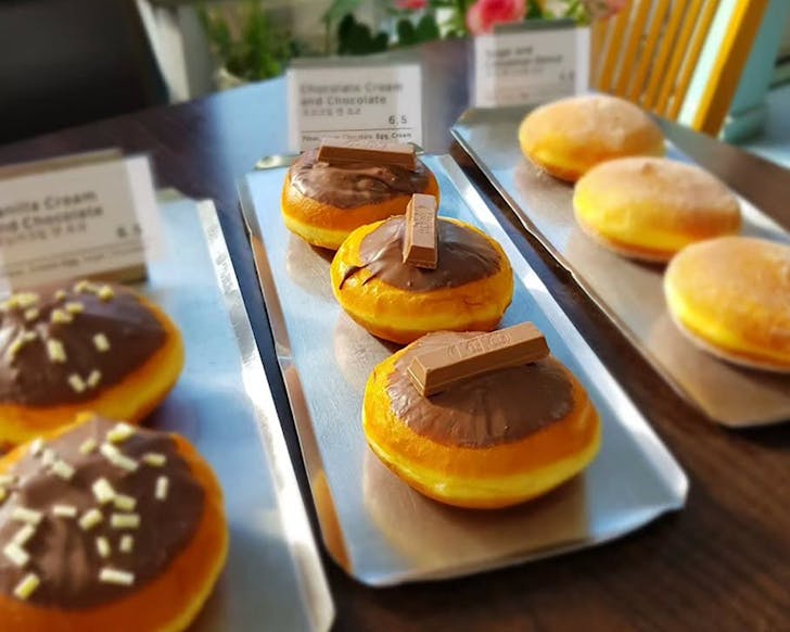 Rows of doughnuts on silver trays at Hoy Hoy bakery. 