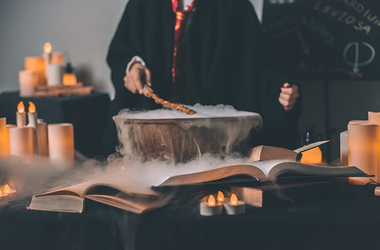 A steaming cauldron and a person waving a wand.