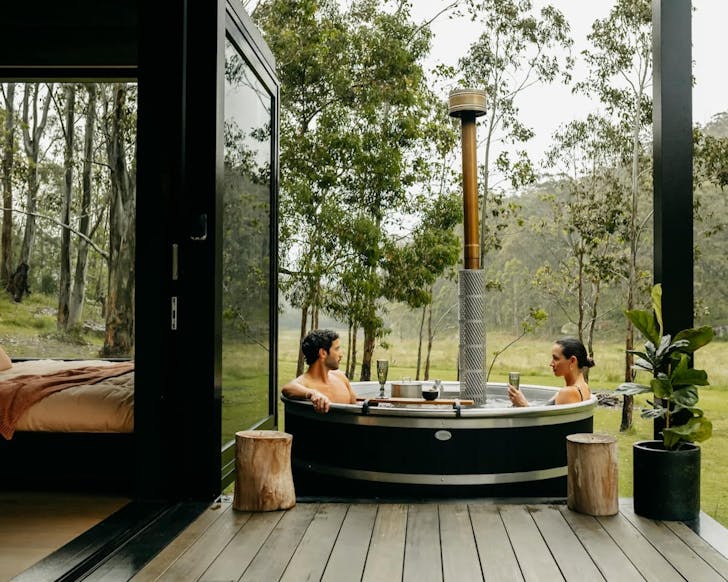 a couple enjoying the wood-fired hot tub at a huch tiny home in the hunter valley