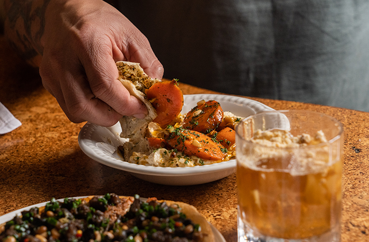 A man dipping bread into hummus.