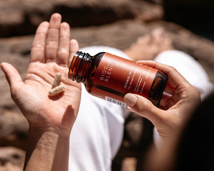Someone tips two iron supplements out of a Bio Blends bottle. 