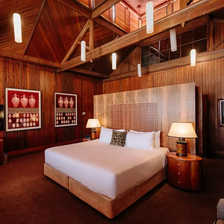 A cosy bed set underneath a timber pitched ceiling. 
