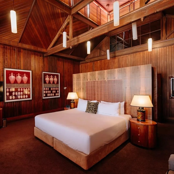A cosy bed set underneath a timber pitched ceiling. 