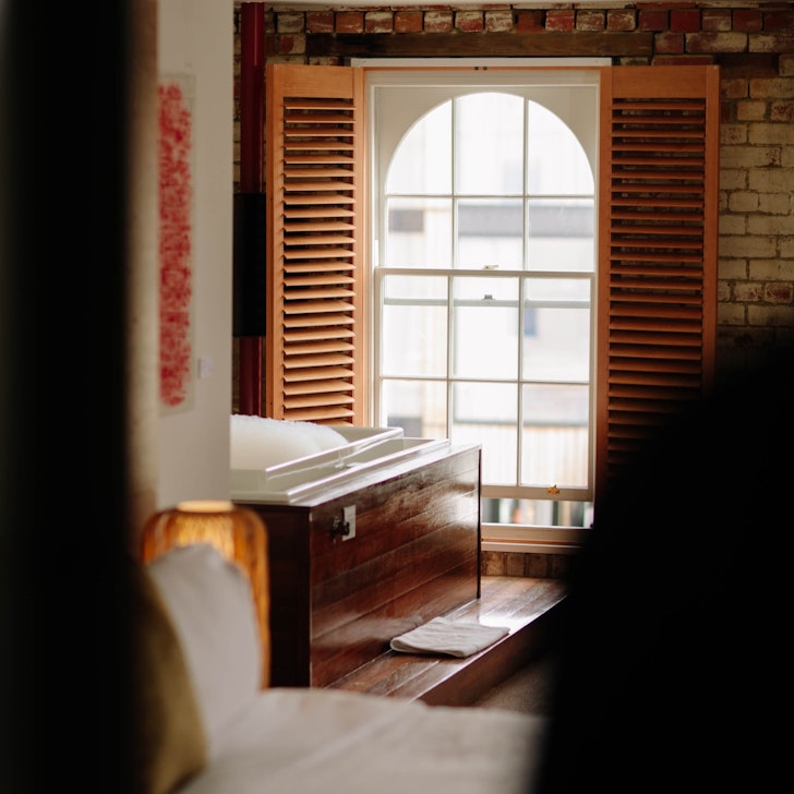 A wooden hot hub by an arched window