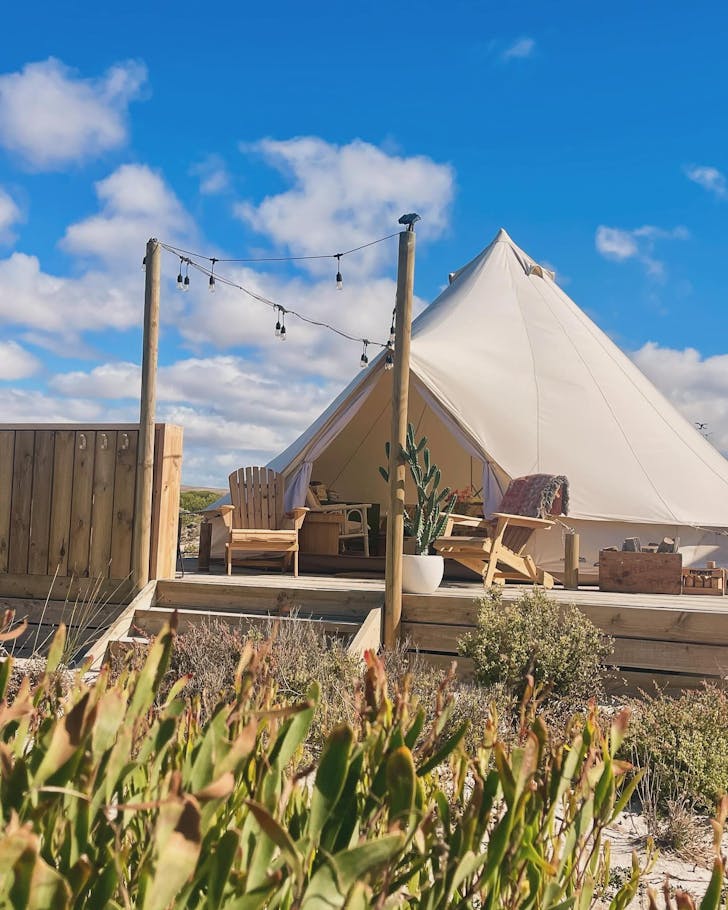 A cream bell tent pitched in the middle of sand dunes