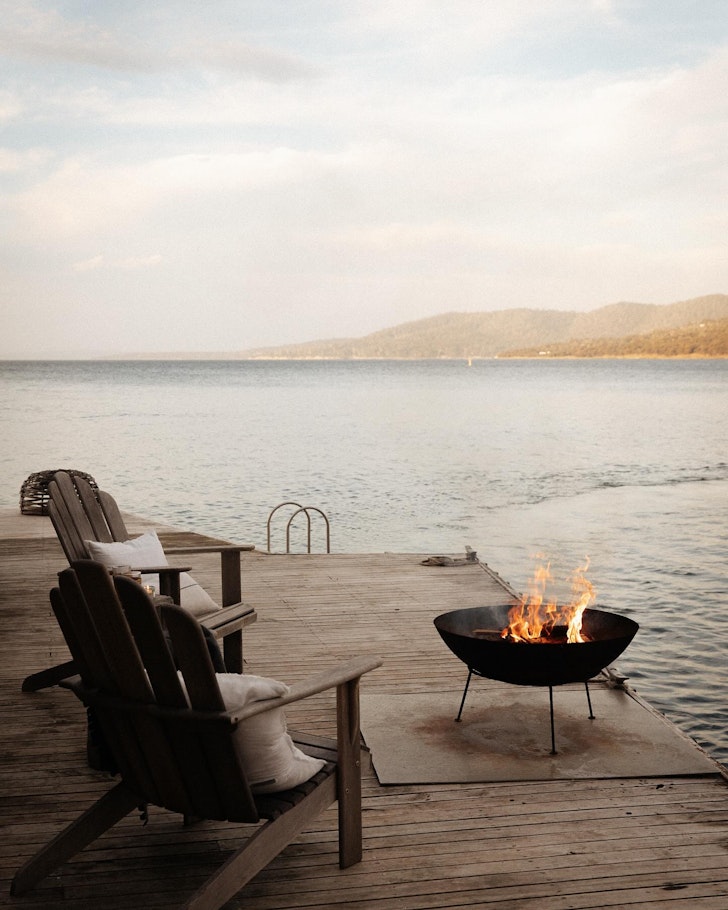 a fire pit on a deck perched on the sea