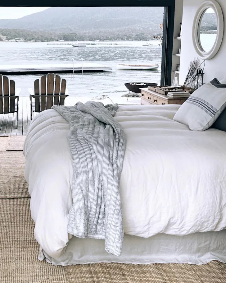 A cosy white bed, perched on the waterfront