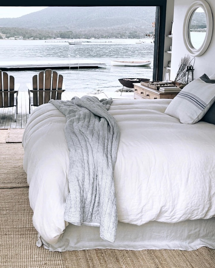 A cosy white bed, perched on the waterfront