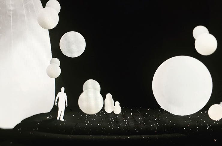 Inflatable, illuminated spheres surround a person standing on their own in a dark room.