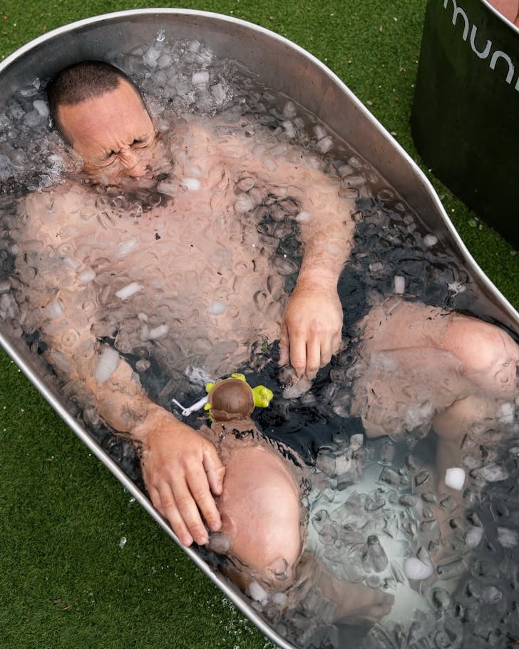 Someone submerges in a metal ice bath.