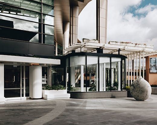 A cafe situated by a large concrete pillar. A concrete sphere sits next to the cafe's outdoor seating.